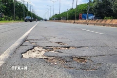 Đường ĐT.741 xuất hiện nhiều "ổ voi, ổ gà" gây nguy hiểm cho người đi đường. (Ảnh: Đậu Tất Thành/TTXVN)