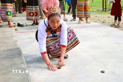 Người tham gia chơi Tó mặng dùng sức bật của các ngón tay để bắn hạt mặng trúng điểm đích phía trước. (Ảnh: Xuân Tiến/TTXVN)