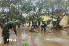 Các chiến sỹ Trung đoàn 6, Bộ Chỉ huy Quân sự thành phố Huế hỗ trợ nhân dân dọn dẹp vệ sinh sau mưa lũ. (Ảnh: Mai Trang/TTXVN)