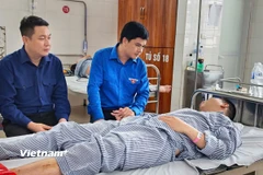Đại diện Đoàn Thanh niên Tập đoàn Công nghiệp Than-Khoáng sản Việt Nam, thăm hỏi, động viên và trao quà cho tấm gương dũng cảm Đinh Đức Hiệp. (Ảnh: Nguyễn Thuấn/Vietnam+)