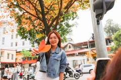 Các bạn trẻ lưu lại khoảnh khắc nên thơ với sắc lá vàng. (Ảnh: Khánh Hòa/TTXVN)
