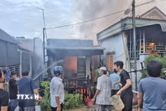 Người dân phối hợp với các lực lượng chức năng nỗ lực khống chế đám cháy, không để lan rộng sang những ngôi nhà liền kề. (Ảnh: TTXVN phát)