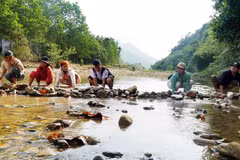 Người dân tập trung về khu vực sông Trường, bê đá đắp đập ngăn dòng chảy để bắt cá. (Ảnh: Lê Phước Ngọc/TTXVN)