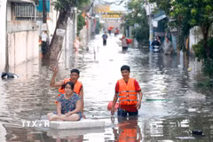 Lực lượng chức năng hỗ trợ người dân những khu vực ngập sâu di dời đến nơi ở khác. (Ảnh: Nguyễn Thanh/TTXVN)