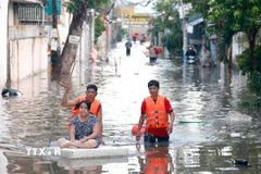 Lực lượng chức năng hỗ trợ người dân những khu vực ngập sâu di dời đến nơi ở khác. (Ảnh: Nguyễn Thanh/TTXVN)
