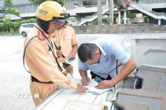 Cảnh sát giao thông lập biên bản một trường hợp tài xế xe khách vi phạm. (Ảnh: Linh Sơn/TTXVN)
