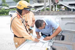 Cảnh sát giao thông lập biên bản một trường hợp tài xế xe khách vi phạm. (Ảnh: Linh Sơn/TTXVN)