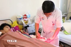 Bác sỹ kiểm tra vết thương của bệnh nhân bị đa tổn thương do pháo tự chế phát nổ gây ra. (Ảnh: Phan Sáu/TTXVN)