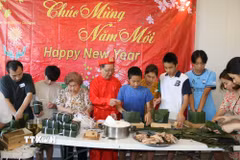 Các em nhỏ gốc Việt tại Australia rất hào hứng và say sưa khi được ông bà, bố mẹ hướng dẫn gói bánh chưng, trao truyền văn hóa Tết dân tộc. (Ảnh: Thanh Tú/TTXVN)