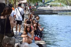 Người dân Paris (Pháp) ngồi kín dọc bờ kênh để tận hưởng bóng mát và không khí dễ chịu hơn gần mặt nước. (Ảnh: Hữu Chiến/TTXVN)