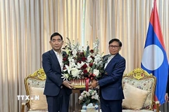 Đại sứ Phạm Việt Hùng (trái) tặng lãng hoa tới Đại sứ Lào Sisavath Inphachanh chúc mừng 50 năm Quốc khánh Lào. (Ảnh: Đỗ Sinh/TTXVN)