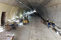 Công nhân và các phương tiện, máy móc thi công các hạng mục bên trong ống hầm. (Ảnh: Hữu Quyết/TTXVN)
