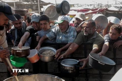 Người dân nhận thức ăn cứu trợ tại thành phố Khan Younis, Dải Gaza. (Ảnh: THX/TTXVN)