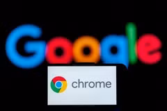 Biểu tượng Chrome trên màn hình điện thoại và biểu tượng Google (phía sau). (Ảnh: Getty Images/TTXVN)