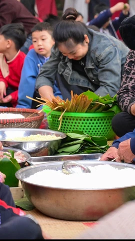 Học sinh Trường Tiểu học Dương Liễu B (Hà Nội) gói trải nghiệm gói bánh chưng ngày Tết dưới sự hướng dẫn của người lớn. (Ảnh: NTCC)