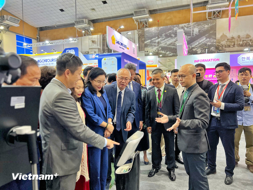 Đại biểu và khách tham quan trải nghiệm gian hàng công nghệ số trong lĩnh vực dịch vụ du lịch tại hội chợ. (Ảnh: Mai Mai/Vietnam+)