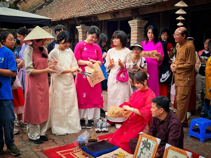 Du khách Hàn Quốc trải nghiệm không gian tranh Đông Hồ được tổ chức ở Đường Lâm, Hà Nội. (Ảnh: Mai Mai/Vietnam+)