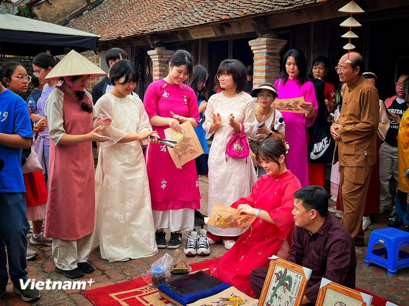 Nhóm du khách Hàn Quốc trải nghiệm với di sản Tranh Đông Hồ của Việt Nam. (Ảnh: Xuân Mai/Vietnam+)