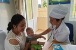 Nhân viên y tế chăm sóc sức khỏe cho trẻ nhỏ. (Ảnh: PV/Vietnam+)
