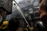 Nhân viên cứu hỏa dập tắt đám cháy còn lại ở Manila, Philippines. (Nguồn: EPA-EFE)