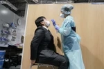 Nhân viên y tế lấy mẫu xét nghiệm COVID-19 tại Narita, Nhật Bản. (Ảnh: AFP/TTXVN)
