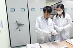 Anh Võ Thiết Cương, Trưởng phòng bảo quản (trái) cho phóng viên xem các trang tư liệu. (Ảnh: Minh Thu/Vietnam+)