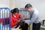 Bác sỹ Pau Kieu Kong đang thăm khám cho bệnh nhi. (Ảnh: Hoàng Nhương/Vietnam+)