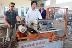 Nhà nông sáng chế Nguyễn Hồng Chương (áo trắng) trong xưởng cơ khí của mình. (Nguồn: Báo Lâm Đồng)