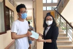 Phó Giám đốc Sở Y tế tỉnh Vĩnh Long Hồ Thị Thu Hằng trao giấy chứng nhận hoàn thành cách ly cho người dân. (Ảnh: Lê Thúy Hằng/TTXVN)