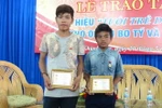Hai em Bo Tý (trái) và Cao Lâm nhận Huy hiệu “Tuổi trẻ dũng cảm.” (Ảnh: Nguyên Lý/TTXVN)