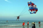 Khách du lịch tham gia trò chơi canô kéo dù tại biển Phạm Văn Đồng (Đà Nẵng). (Ảnh: Trần Lê Lâm/TTXVN) 