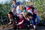 Người di cư vượt qua hàng rào dây thép gai gần Roszke, giáp giới Serbia ngày 27/8. (Nguồn: AFP/TTXVN)