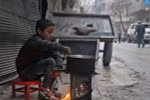 Một em bé Syria nấu ăn trên đường phố Aleppo. (Nguồn: AFP/TTXVN)