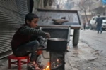 Một em bé Syria nấu ăn trên đường phố Aleppo. (Nguồn: AFP/TTXVN)