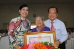 Bí thư Thành ủy TP. Hồ Chí Minh Lê Thanh Hải trao tặng danh hiệu "Bà mẹ Việt Nam Anh hùng” cho Mẹ Dương Thị Tình tại buổi lễ. (Ảnh: Thanh Vũ/TTXVN)
