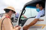 Cảnh sát giao thông kiểm tra giấy tờ của một phương tiện chở hàng hóa ngay tại chốt kiểm soát dịch COVID-19. (Ảnh: Minh Sơn/Vietnam+) 