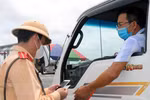 Cảnh sát giao thông kiểm tra giấy tờ của một phương tiện chở hàng hóa ngay tại chốt kiểm soát dịch COVID-19. (Ảnh: Minh Sơn/Vietnam+) 