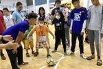 Các chuyên viên can thiệp hướng dẫn trẻ tự kỷ chơi bóng đá. (Ảnh: Đinh Hằng/TTXVN)