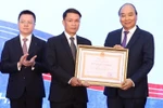 Thủ tướng Nguyễn Xuân Phúc, Chủ tịch Hội đồng Thi đua-Khen thưởng Trung ương, trao tặng Huân chương Lao động hạng Nhất cho Thông tấn xã Việt Nam. (Ảnh: Thống Nhất/TTXVN)