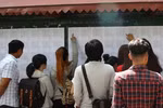 Thí sinh xem số báo danh và phòng thi tại điểm thi trường THPT chuyên Quốc học Huế. (Ảnh: Tường Vi/TTXVN)