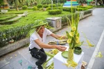 Cứ chiều chiều bên cạnh vườn hoa Hà Đông (Hà Nội), nhiều người dân Thủ đô lại tò mò thấy một người đàn ông đang tỉ mẩn tỉa tót từng chiếc lá dừa thành hình dáng chú chuồn chuồn, cánh bướm hay chú cào cào. (Ảnh: Thế Đại/Vietnam+)