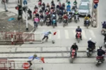Trên đường Giải Phóng, mặc dù có rào chắn cẩn thận nhưng khi tàu chuẩn bị chạy qua, nhiều người dân vẫn bất chấp tính mạng vượt qua. (Ảnh: Minh Sơn/Vietnam+)