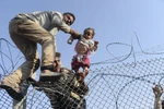 Người di cư Syria cố vượt qua hàng rào dây thép gai để vào lãnh thổ Thổ Nhĩ Kỳ ngày 14/6. (Nguồn: AFP/TTXVN)