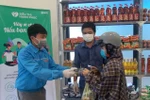 Người nghèo nhận hàng hóa và khẩu trang miễn phí. (Ảnh: Xuân Triệu/TTXVN)