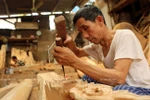 Ông Nguyễn Chí Đường thôn Phù Yên (xã Trường Yên, huyện Chương Mỹ) chạm khắc một chi tiết gỗ. (Ảnh: Trịnh Bộ/Báo ảnh Việt Nam)