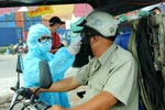 Nhân viên y tế đo thân nhiệt người ra vào Thành phố Hồ Chí Minh tại chốt kiểm dịch. (Ảnh: Đinh Hằng/TTXVN)