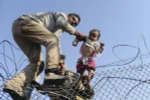 Người di cư Syria cố vượt qua hàng rào dây thép gai để vào lãnh thổ Thổ Nhĩ Kỳ. (Nguồn: AFP/TTXVN)