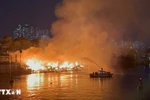 Cảnh sát Phòng cháy chữa cháy sử dụng ca nô chuyên dụng để phun nước vào đám cháy. (Ảnh: TTXVN)