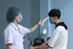 Lực lượng y tế đo thân nhiệt người dân khi vào bệnh viện. (Ảnh: Hoàng Hùng/TTXVN) 