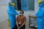 Nhân viên y tế quận Bình Thạnh lấy mẫu xét nghiệm cho người làm việc tại sân bay Tân Sơn Nhất, tối 7/2. (Ảnh: Đinh Hằng/TTXVN)